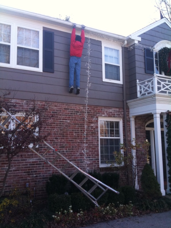 Man appears to be hanging from gutter after ladder fell while stringing Christmas lights
